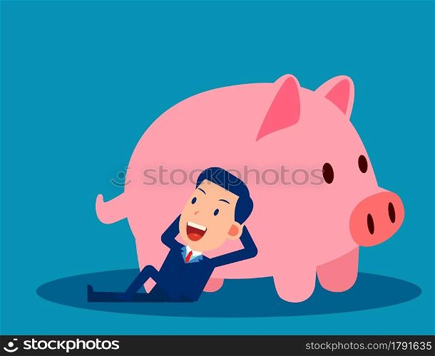 A businessman reclines close to the piggy bank. Saving money concept