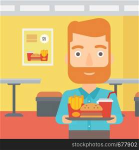 A hipster man with the beard holding a tray full of junk food on a cafe background vector flat design illustration. Square layout.. Man with fast food.