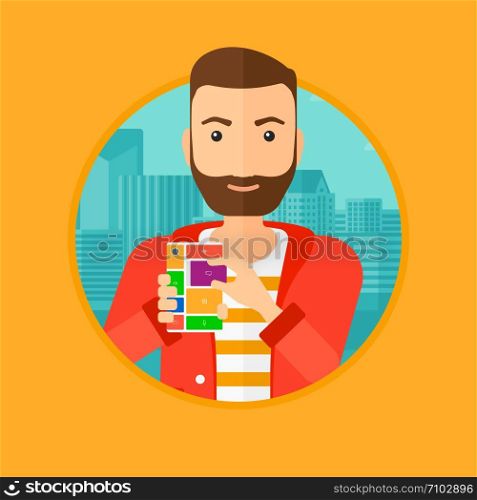 A hipster man with the beard holding modular phone. Young man with modular phone on a city background. Man using modular phone. Vector flat design illustration in the circle isolated on background.. Man with modular phone.
