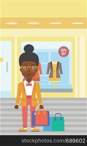 African-american woman holding shopping bags on the background of boutique window with dressed mannequins. Happy young woman carrying shopping bags. Vector flat design illustration. Vertical layout.. Happy woman with bags vector illustration.