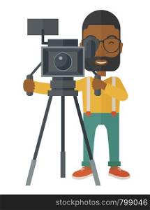 An african-american cameraman with beard and glasses looking through movie camera on a tripod vector flat design illustration isolated on white background. Vertical layout.. Cameraman.