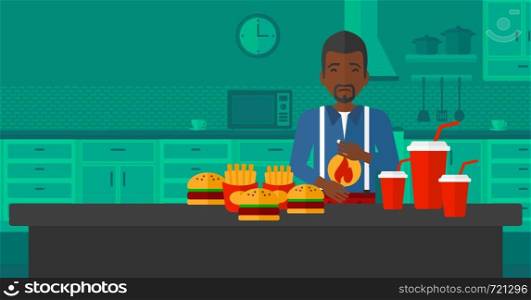 An african-american man standing in front of table full of junk food and suffering from heartburn on a kitchen background vector flat design illustration. Horizontal layout.. Man suffering from heartburn.