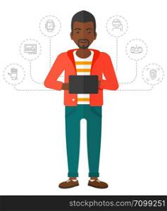 An african-american man standing with a tablet computer and some icons connected to the laptop vector flat design illustration isolated on white background. . Man holding tablet.