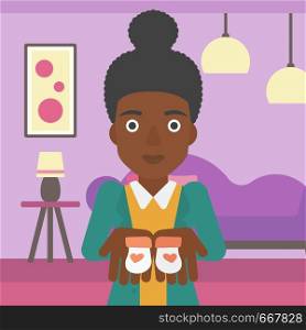 An african-american pregnant woman holding baby booties in hands on the background of living room. Vector flat design illustration. Square layout.. Pregnant woman with baby booties.