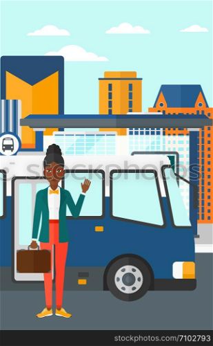 An african-american woman standing at the entrance door of bus on the background of bus stop with skyscrapers behind vector flat design illustration. Vertical layout.. Woman standing near bus.