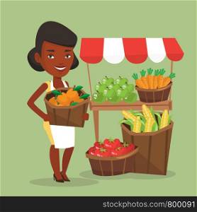 An african greengrocer standing near stall with fruits and vegetables. Greengrocer standing near market stall. Greengrocer holding basket with fruits. Vector flat design illustration. Square layout.. Street seller with fruits and vegetables.