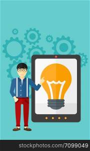 An asian man pointing at a big tablet computer with a light bulb on a screen on a blue background with cogwheels vector flat design illustration. Vertical layout.. Man pointing at tablet computer with light bulb on screen.