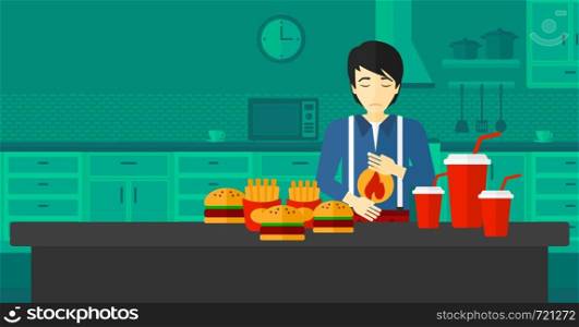 An asian man standing in the kitchen in front of table full of junk food and suffering from heartburn vector flat design illustration. Horizontal layout.. Man suffering from heartburn.