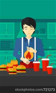 An asian man standing in the kitchen in front of table full of junk food and suffering from heartburn vector flat design illustration. Vertical layout.. Man suffering from heartburn.