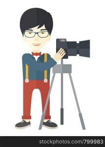An asian photographer in glasses standing with camera on a tripod vector flat design illustration isolated on white background. Vertical layout.. Photographer.