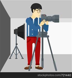 An asian photographer working with camera on the background of photo studio with lighting equipment vector flat design illustration. Square layout.. Photographer working with camera on a tripod.