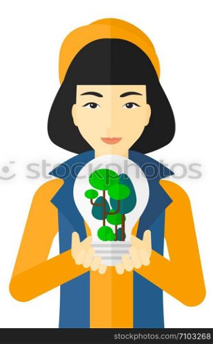 An asian woman holding in hands a big lightbulb with trees inside vector flat design illustration isolated on white background. . Woman with lightbulb and trees inside.