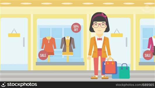 An asian woman holding shopping bags on the background of boutique window with dressed mannequins. Happy woman carrying shopping bags. Vector flat design illustration. Horizontal layout.. Happy woman with bags vector illustration.