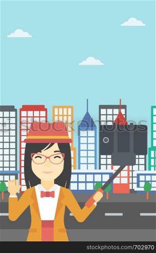 An asian woman making selfie with a selfie-stick. An asian woman taking photo with cellphone and waving on a city background. Vector flat design illustration. Vertical layout.. Woman making selfie vector illustration.