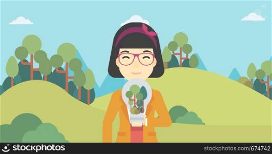 An asian woman standing on the background of green forest and holding in hands a big lightbulb with trees inside. Green energy concept. Vector flat design illustration. Horizontal layout.. Woman with lightbulb and trees inside.