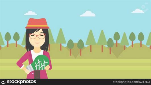 An asian woman standing on the background of green forest and holding in hands a big light bulb with small wind turbines inside. Vector flat design illustration. Horizontal layout.. Woman holding lightbulb with windmills inside.