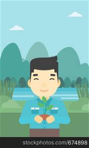 An asian young man holding in hands a small plant in soil on the background of landscape with mountains and river. Vector flat design illustration. Vertical layout.. Man holding plant vector illustration.