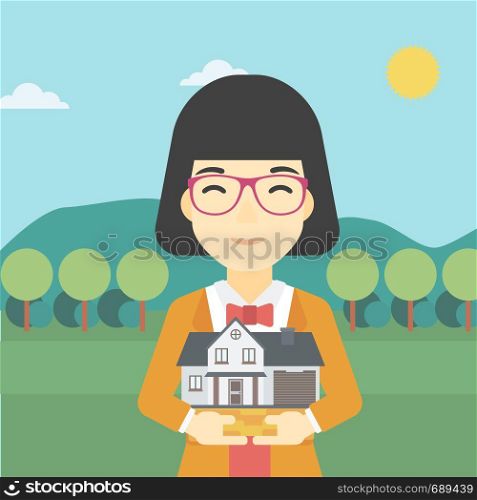 An asian young woman holding house model in hands on the background of mountains. Real estate agent with house model in hands. Vector flat design illustration. Square layout.. Woman holding house model vector illustration.