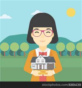 An asian young woman holding house model in hands on the background of mountains. Real estate agent with house model in hands. Vector flat design illustration. Square layout.. Woman holding house model vector illustration.