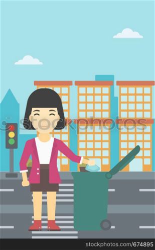 An asian young woman throwing away a garbage in a green trash in the city. Woman throwing away trash. Eco-friendly woman throwing trash. Vector flat design illustration. Vertical layout.. Woman throwing away trash vector illustration.