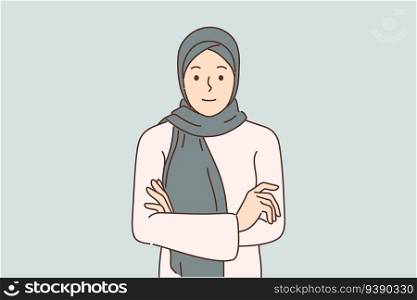 Arab woman in hijab stands with arms crossed and looks at screen for concept muslim style in clothing and diversity in fashion. Beautiful girl in hijab covering hair to comply with ethnic traditions. Arab woman in hijab stands with arms crossed and looks at screen for concept diversity in fashion