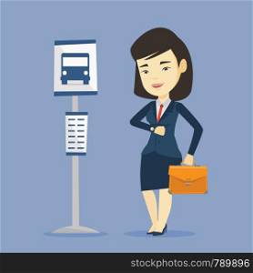 Asian business woman with briefcase waiting at the bus stop. Young business woman standing at the bus stop. Woman looking at her watch at the bus stop. Vector flat design illustration. Square layout.. Woman waiting at the bus stop vector illustration.
