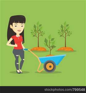 Asian gardener with wheelbarrow standing on the background of newly planted trees. Young gardener pushing wheelbarrow with tree and dirt in the park. Vector flat design illustration. Square layout.. Woman pushing wheelbarrow with plant.