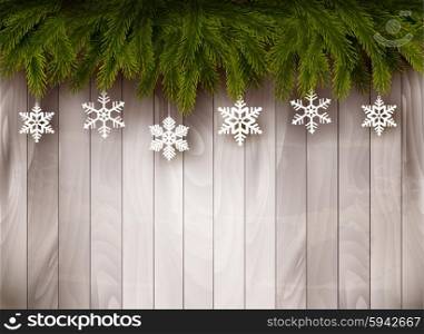 Background with Christmas tree branches and snowflakes in front of a wooden wall. Vector.
