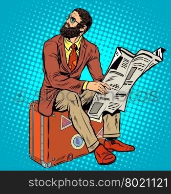 Bearded hipster traveler reading a newspaper pop art retro style. Retro hipster sitting on a suitcase. Bearded businessman. Bearded hipster traveler reading a newspaper