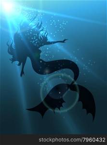 Beautiful long haired mermaid in deep water against sun beams.