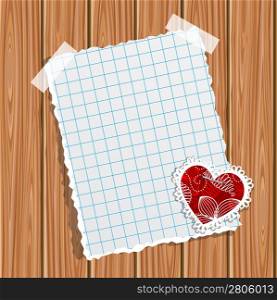 Blank notebook paper and small valentine on a wooden wall