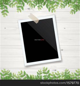 Blank photo frame or picture frame with framing of green leaves and wooden texture background. Realistic vector illustration.