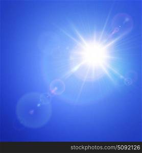 Bright sun in blue sky with lens flare effect