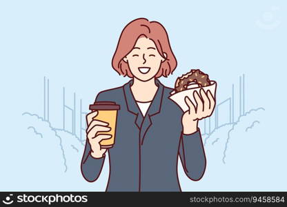 Business woman having breakfast donut and drinking coffee standing on city street and enjoying dessert on way to work. Happy girl eating breakfast on go buying takeaway food at bakery. Business woman having breakfast donut and drinking coffee standing on street and enjoying dessert