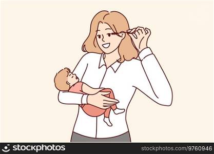 Business woman mother holds baby in arms and does makeup at same time, keeping balance between family and career. Successful woman holding newborn son and getting ready to go to work. Business woman mother holds baby and does makeup, keeping balance between family and career