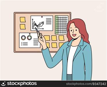 Businesswoman demonstrates financial graphs and charts pinned on cork board in office. Businesswoman boasts about growth of company income and number of clients that bring income to business.. Businesswoman demonstrates financial graphs and charts pinned on cork board in office
