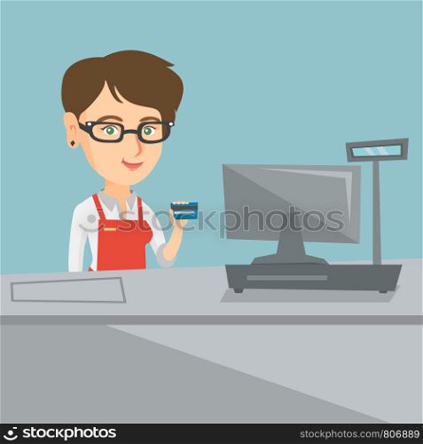 Caucasian smiling cashier standing at the checkout and holding a credit card. Young cashier making payment by credit card. Cashier showing a credit card. Vector cartoon illustration. Square layout.. Young caucasian cashier holding a credit card.