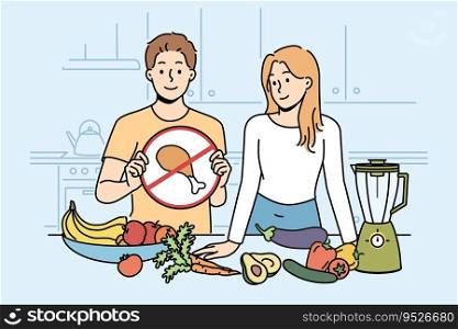 Cooking vegan show with man and woman standing in kitchen with vegetables and demonstrating crossed out meat sign. Guy and girl are preparing vegetarian dish, recommend diet of healthy food. Cooking vegan show with man and woman standing in kitchen with vegetables and without meat
