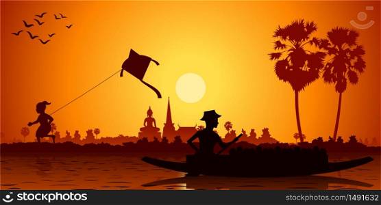 Country life of Asia boy playing with kite and man rows boat to go back home. Sunset time silhouette style