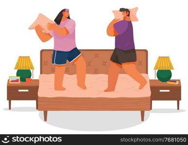 Couple fighting pillows, playing childhood game, have fun together at home, man and woman rejoice standing at bed, two adult friends playing, romance fighting of pillows of girlfriend and boyfriend. Couple fighting pillows, playing childhood game, have fun together at home, man and woman rejoice