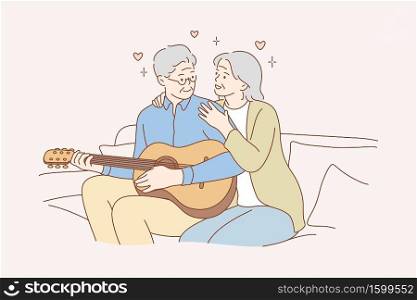 Couple, love, play, romance, music, recreation concept. Romantic old man and woman senior citizens pensioners sitting on couch together and playing guitar musical instrument at home. Happy retirement.. Couple, love, play, romance, music, recreation concept