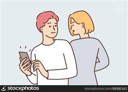 Curious woman trying to spy on boyfriend chatting or using social media on phone. Guy with phone looks back at girlfriend violating personal space and spy because of jealousy or distrust . Curious woman trying to spy on boyfriend chatting or using social media on phone