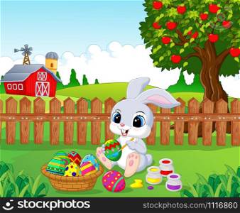 Cute Easter Bunny painting an egg in the garden