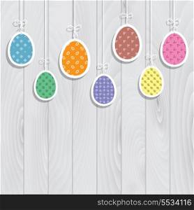 Cute Easter eggs hanging against a wooden texture background