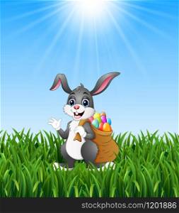 Easter bunny rabbit with easter eggs a sack of full in the grass background