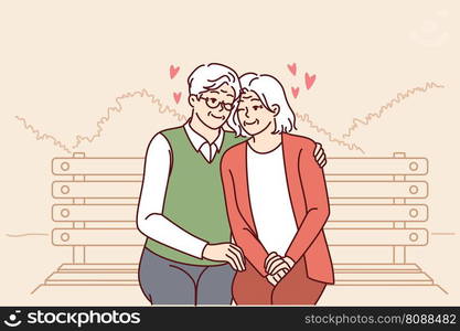 Elderly couple in love sits on park bench hugging and enjoying happy family life. Relationship between elderly man and woman in love sitting hugging and having fun from retirement.. Elderly couple in love sits on park bench hugging and enjoying happy family life