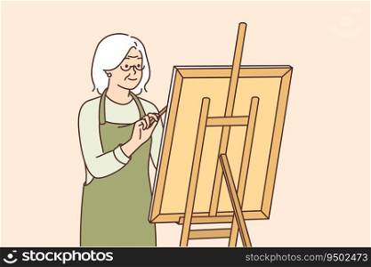 Elderly woman artist stands near easel and draws picture enjoying creative hobby after retiring. Gray-haired grandmother is fond of drawing and dreams of becoming famous artist or selling own artworks. Elderly woman artist stands near easel and draws picture enjoying creative hobby after retiring