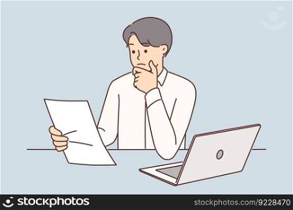 Embarrassed businessman with documents from bank sitting at table with laptop and touching chin ponders over solution to problem. Man is confused by notice from tax office or bank that has debt . Embarrassed businessman with documents from bank or tax office sitting at table with laptop 