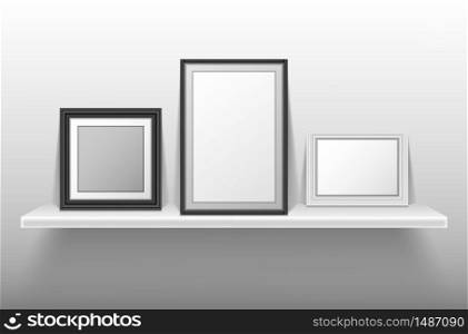 Empty photo frames standing on white shelf. Vector realistic mockup of interior decoration with blank pictures with white and black border. Bookshelf with image frames for home, gallery or portfolio. Empty photo frames standing on white shelf