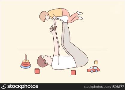 Family, fatherhood, childhood, play, recreation, leisure concept. Joyful young man dad lying on carpet floor lifting excited happy little child kid son at home. Having fun and fathers day illustration. Family, fatherhood, childhood, game, recreation, support, leisure concept